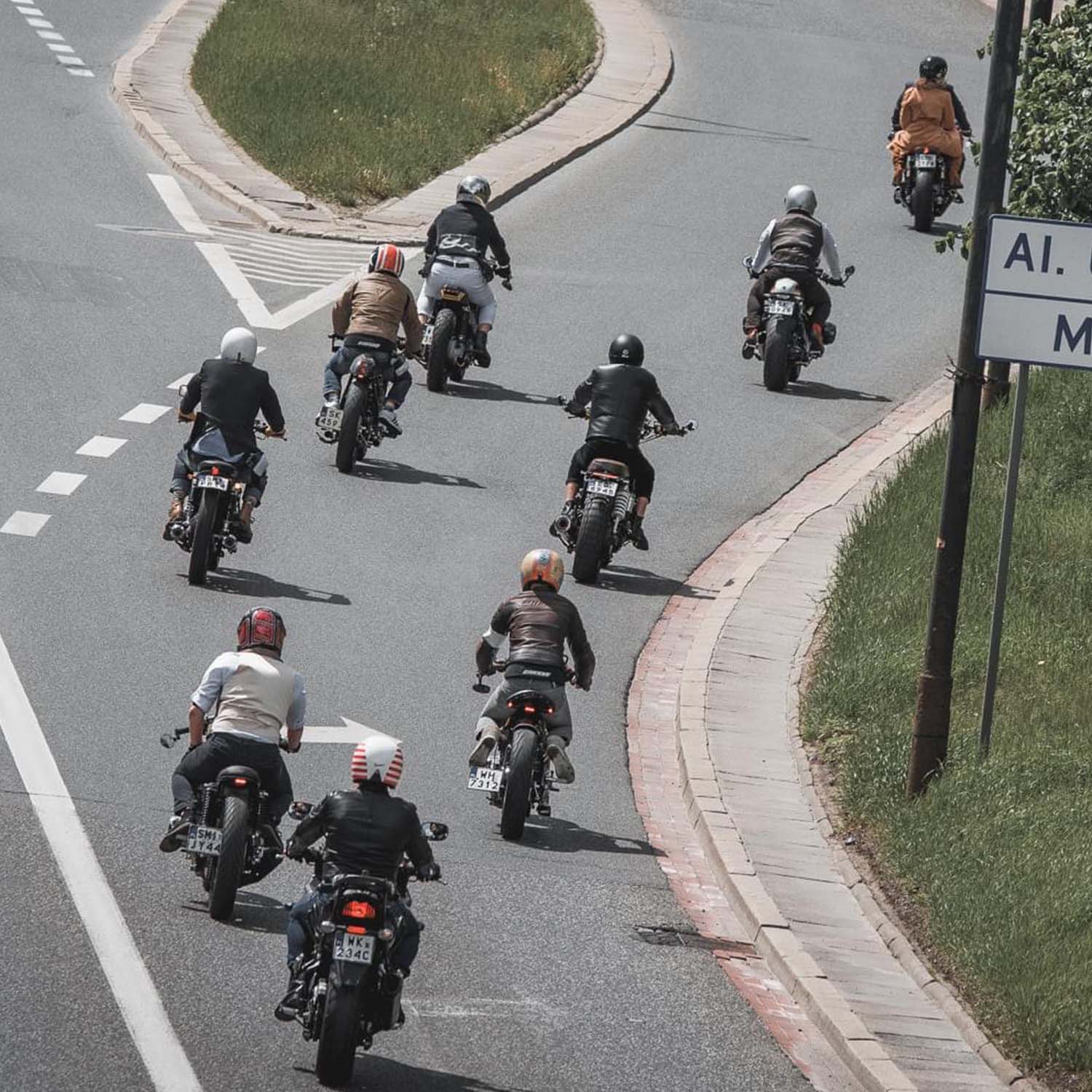 A pack of custom motorcycles seen from above sweeping through a curve on a Warsaw road