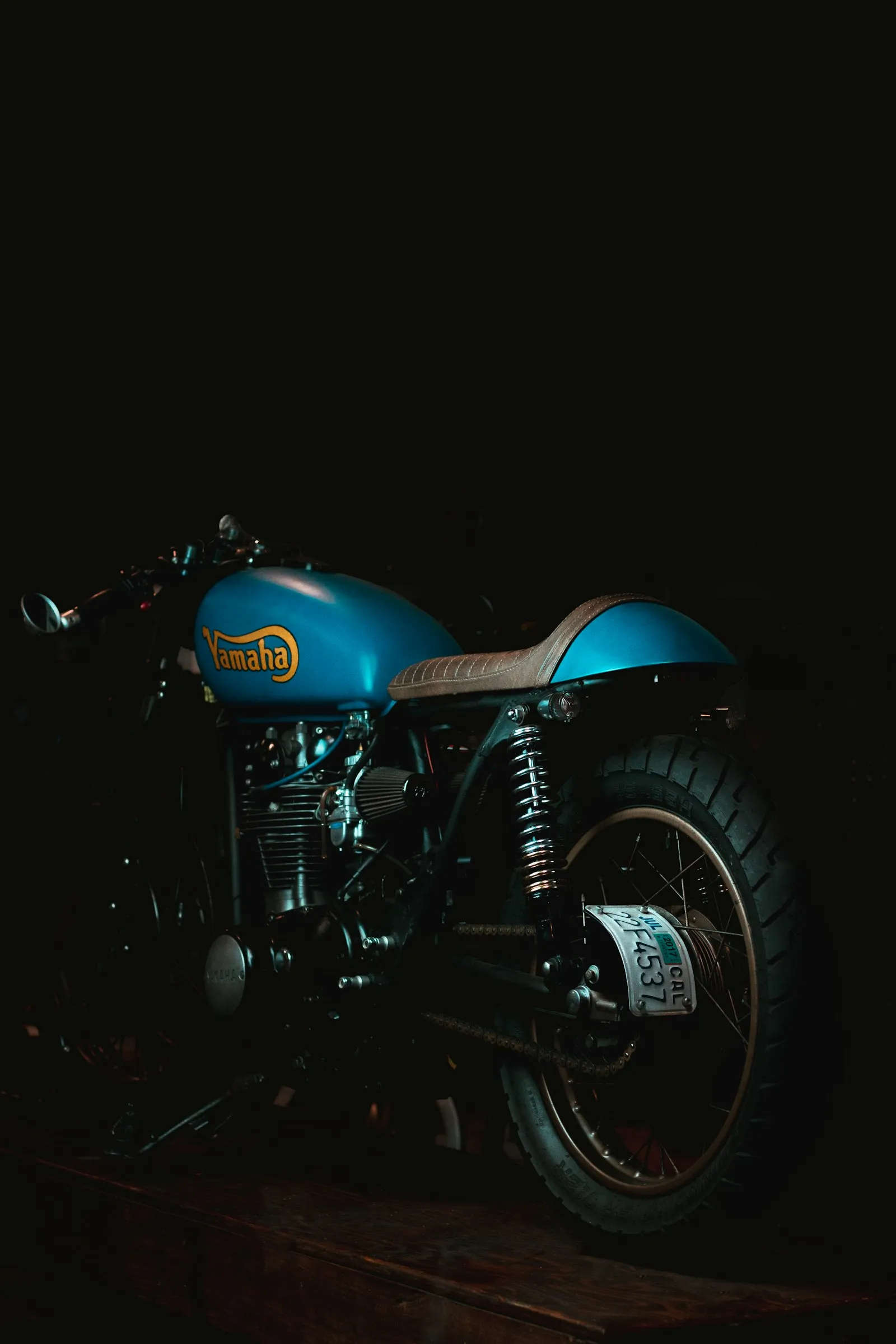 Vintage motorcycle with orange spoked wheels against a brick wall